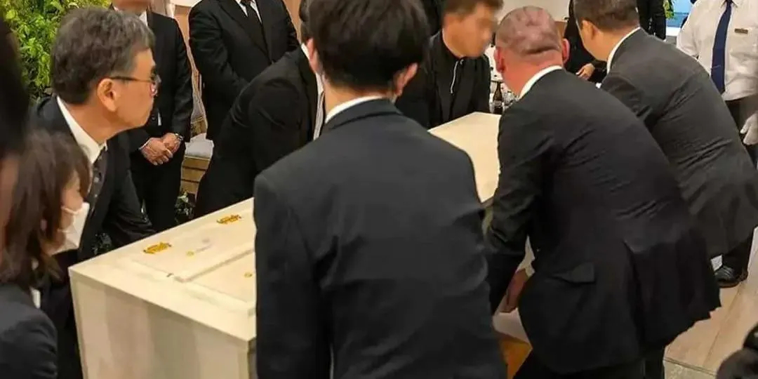 白い棺を囲んで、喪服の参列者がお別れをする火葬式の写真